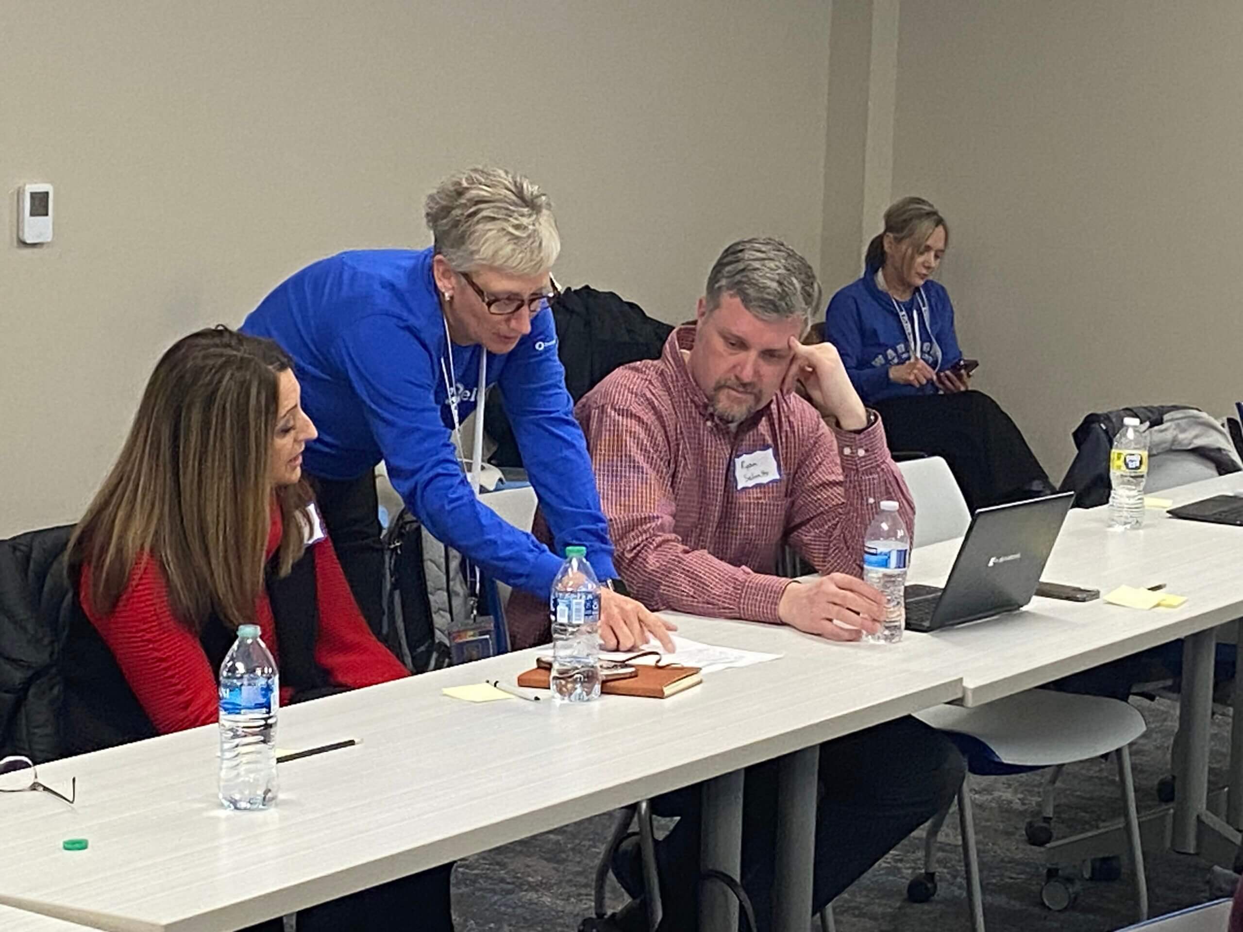 A woman helping two teachers with a topic.