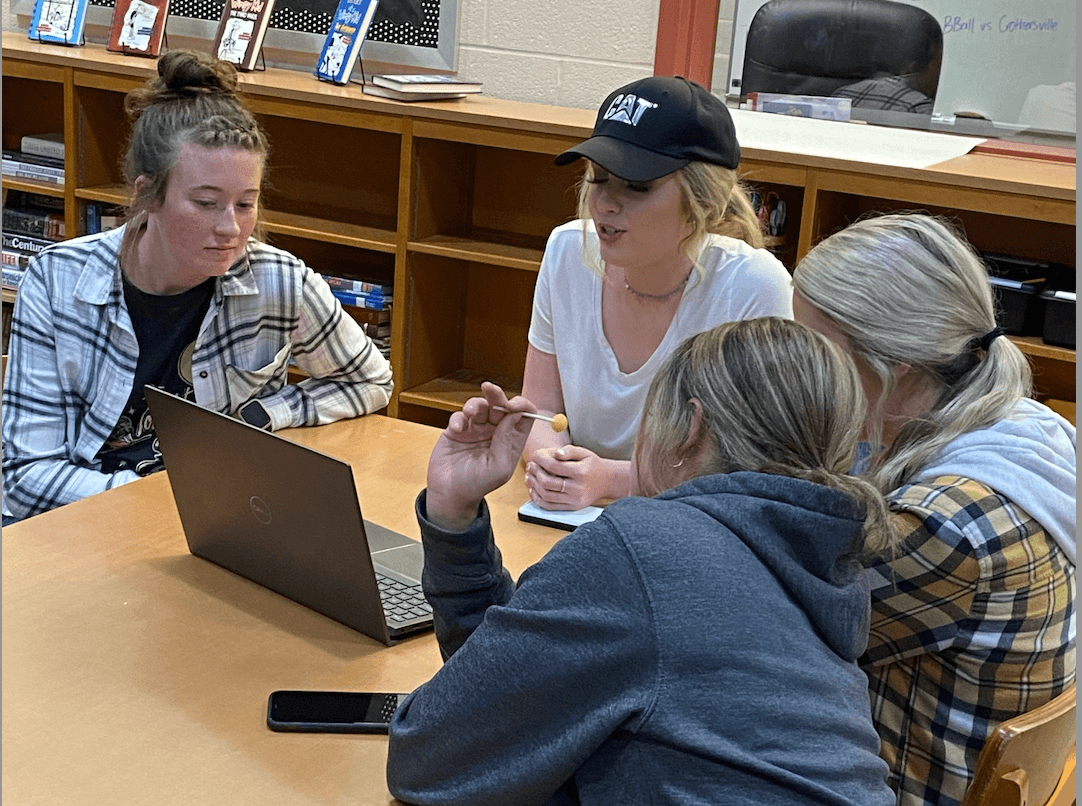 A woman looking at her computer while 3 teachers talk to her.