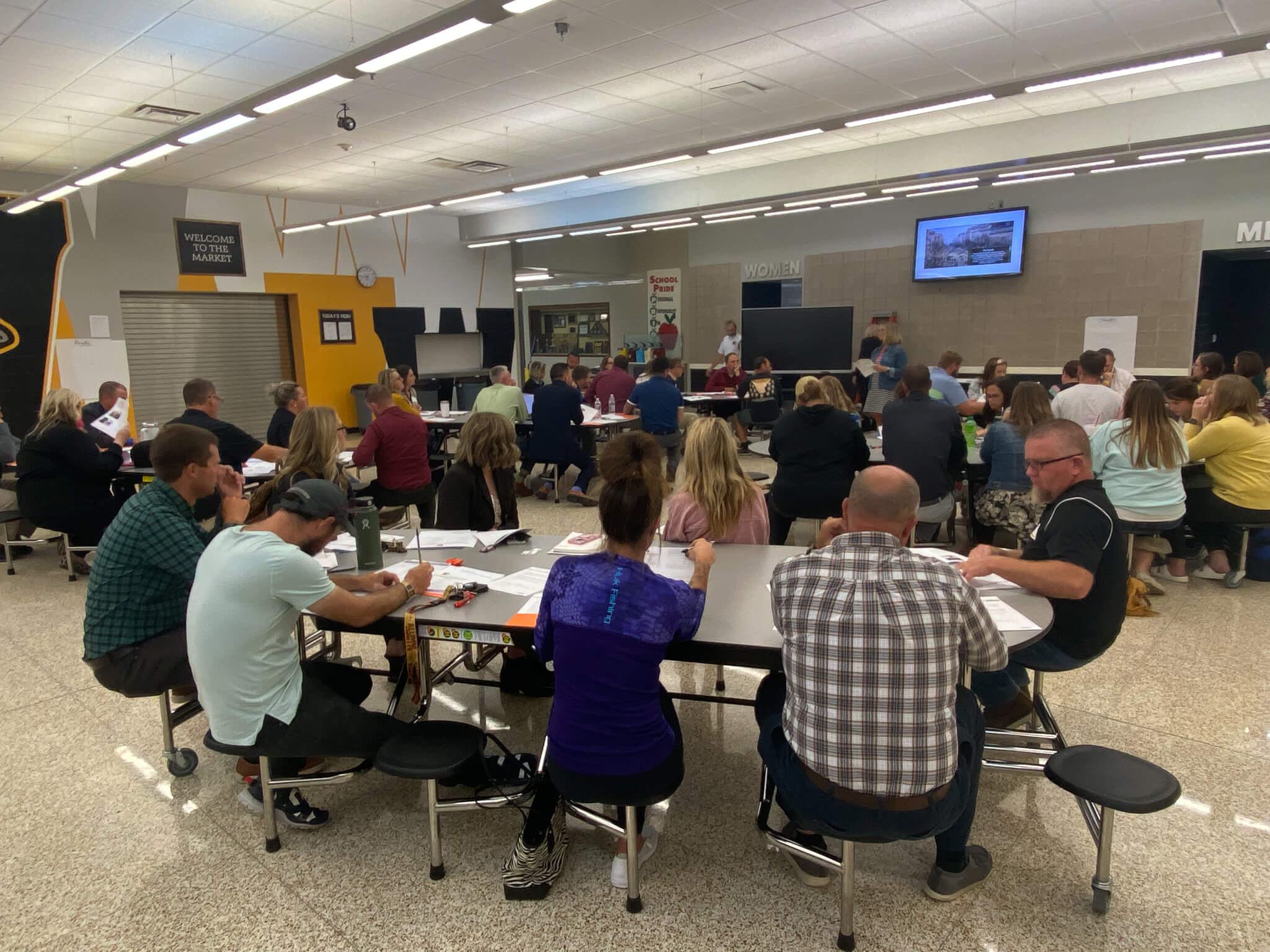 People sitting at tables in a large room talking.