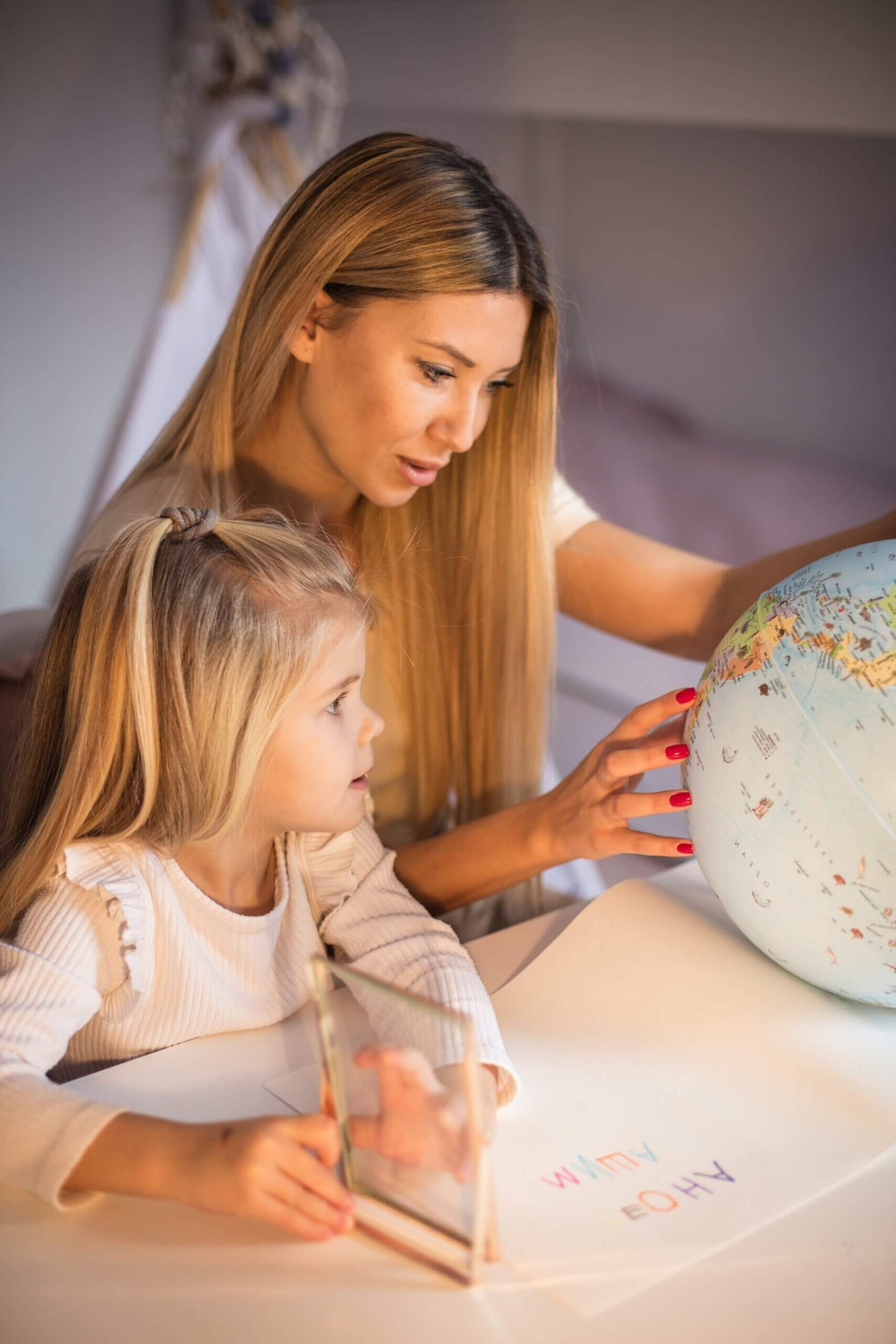 A woman and girl looking at a globe.