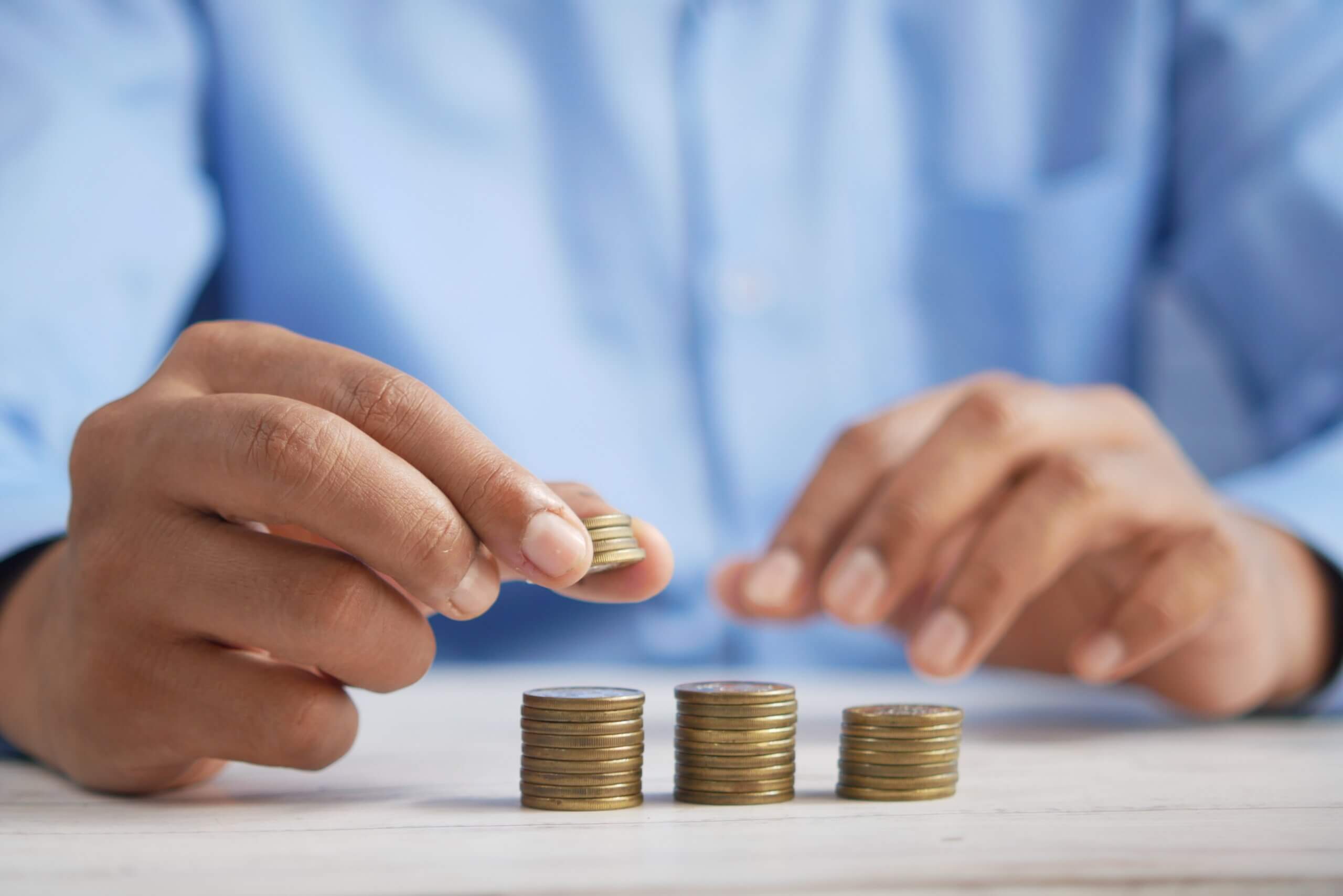 A man in blue staking coins into piles